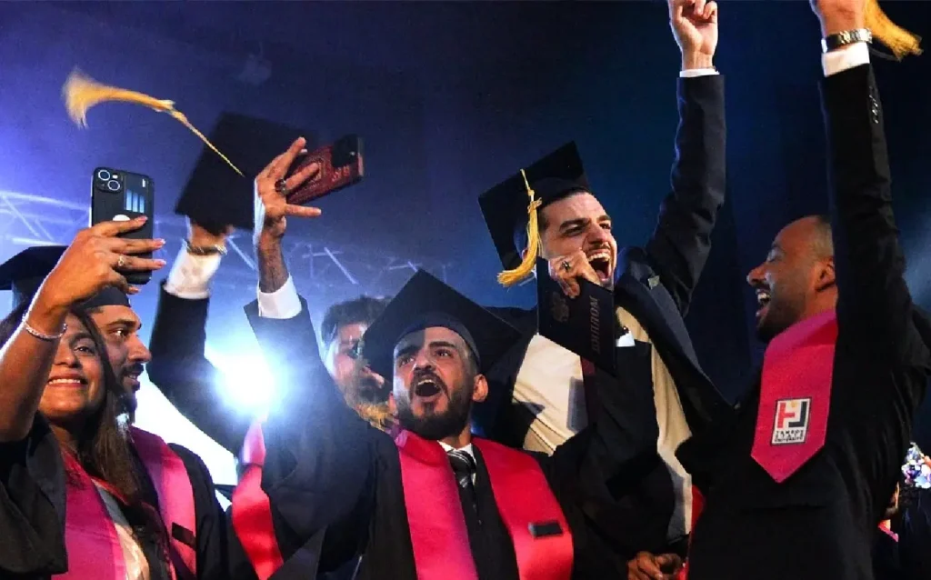 “International medical students celebrating graduation with caps and certificates on stage.”